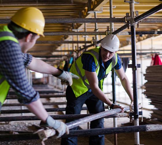 two construction workers discussing scaffolding safety on a site wearing hard hats and reflective vests six safety procedures in action